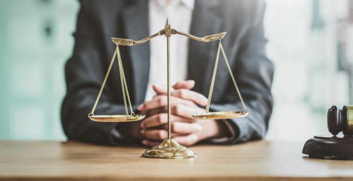 Close,Up,Golden,Scales,With,Blurry,Lawyer,As,Background.
