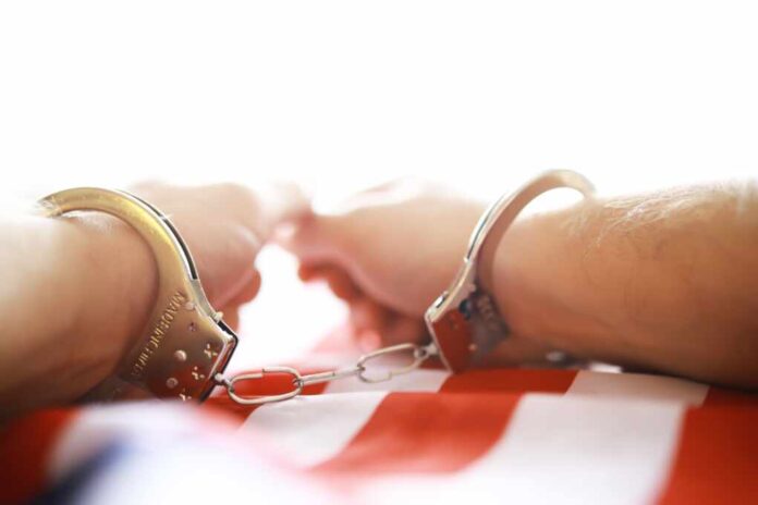 Close-up,Of,Handcuffed,Hands,On,American,Flag,Background,In,Bright