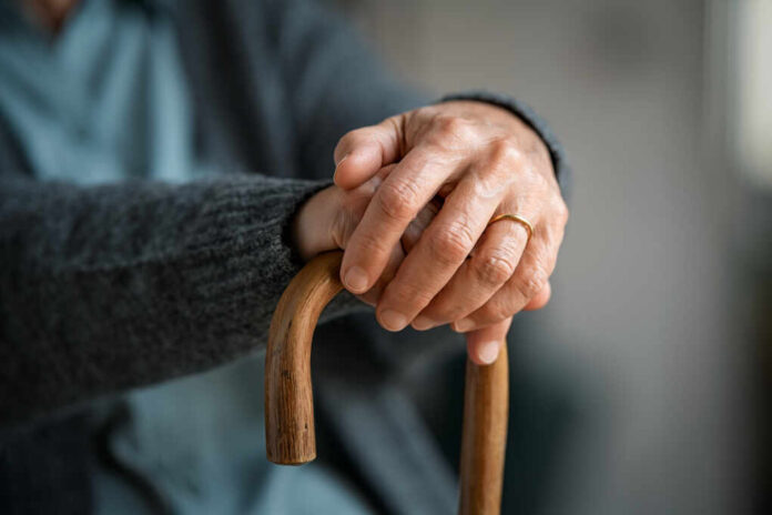 Close,Up,Of,Senior,Disabled,Woman,Hands,Holding,Walking,Stick.