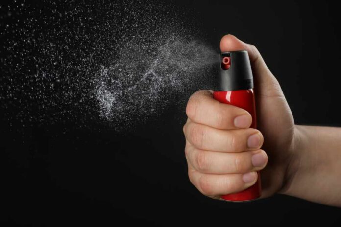 Man,Using,Pepper,Spray,On,Black,Background,,Closeup
