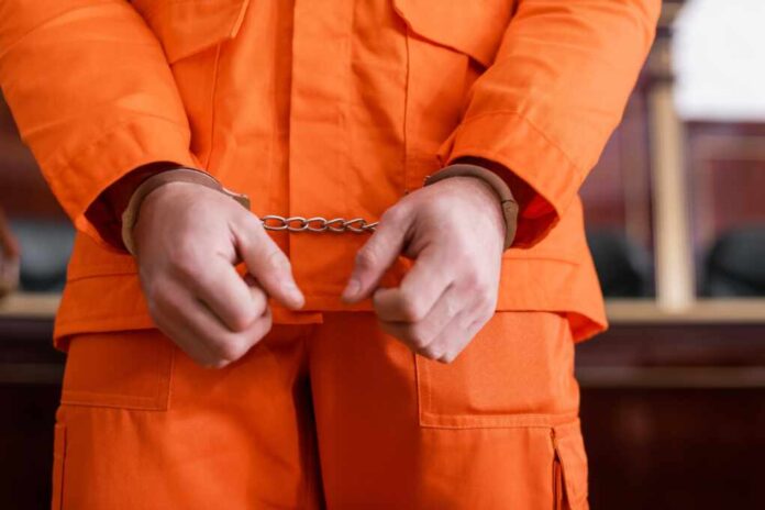 Cropped,View,Of,Accused,Man,In,Handcuffs,And,Orange,Jail