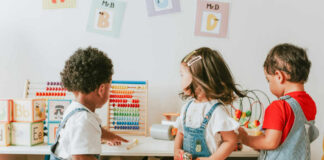 Three children engaged in play with educational toys in a colorful classroom
