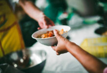 Immune Soups: Are They Really A Cure-All? A person handing a bowl of food to another person in a communal setting