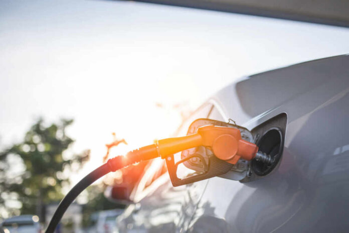 A fuel nozzle inserted into a cars gas tank during sunset