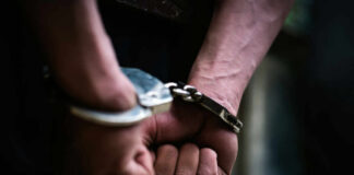 Close-up of hands in handcuffs, indicating an arrest