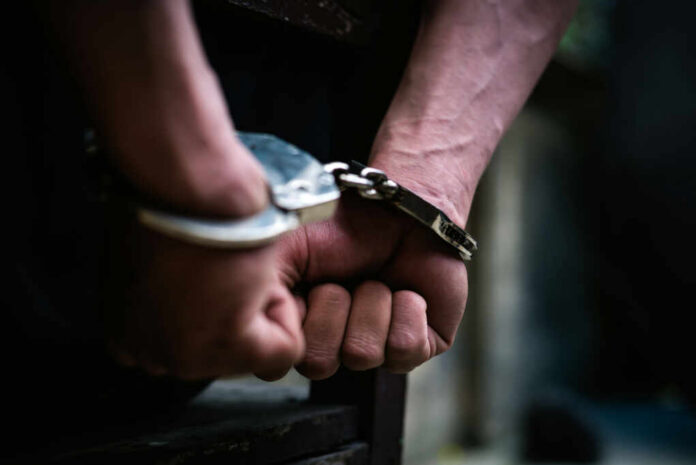 Close-up of hands in handcuffs, indicating an arrest