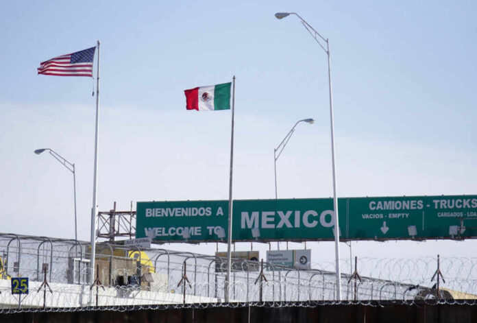 Flags of the United States and Mexico at a border crossing with a welcome sign