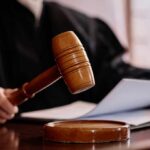A judges gavel poised above a wooden block with a document in the background