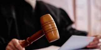A judges gavel poised above a wooden block with a document in the background