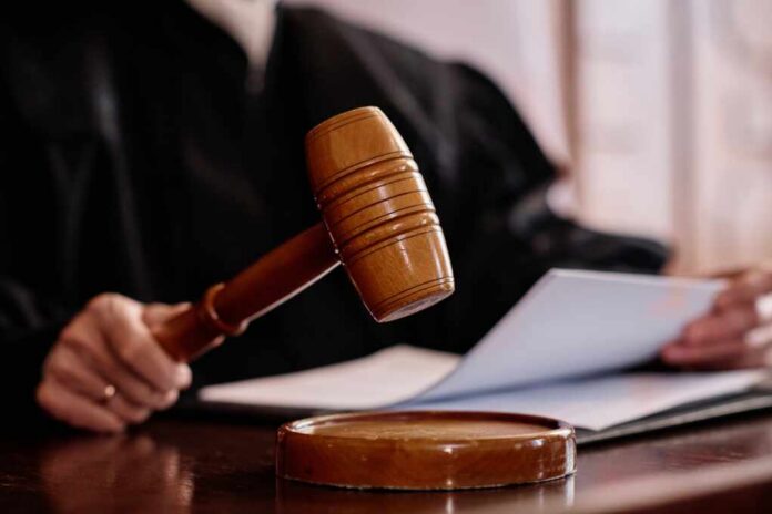 A judges gavel poised above a wooden block with a document in the background