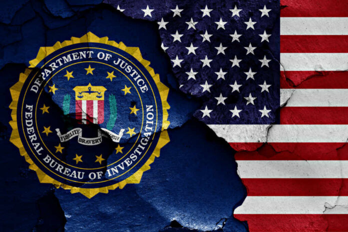 FBI emblem partially obscured by a cracked wall with an American flag background