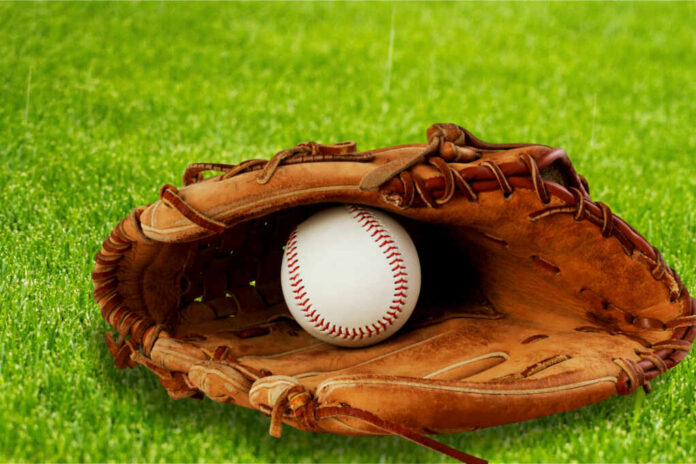 A baseball glove with a baseball resting inside, set on green grass