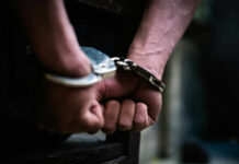Close-up of hands in handcuffs, indicating an arrest