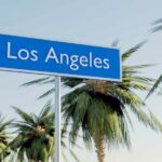 LA’s Wage War: FAILED Promises Unfold Sign indicating Los Angeles with palm trees in the background