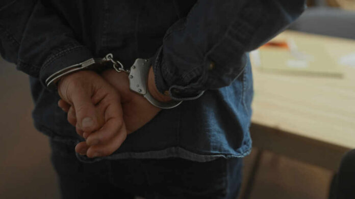 Hands behind back in handcuffs, indicating an arrest