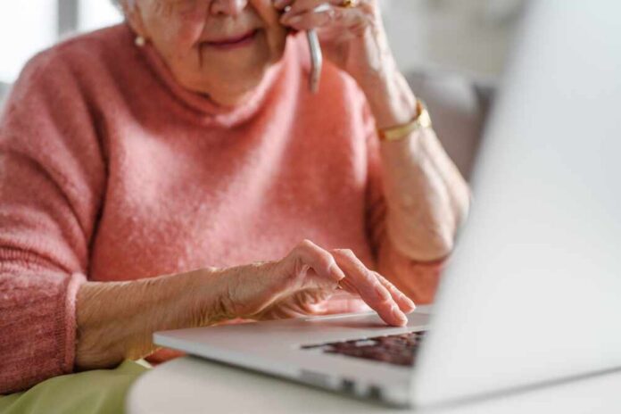 Elderly woman on a phone call while using a laptop