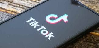 Close-up of a smartphone displaying the TikTok logo on a wooden surface