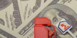 Red fuel pump toy next to hundred dollar bills