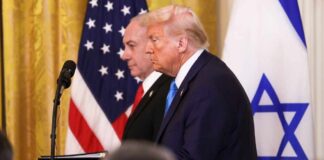 Donald Trump and another official at a press conference with flags in the background