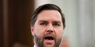 A man in a suit passionately speaking at a podium