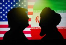 Trump Declares Iran War WON—One Hour Silhouettes of two figures against the backgrounds of the American and Iranian flags