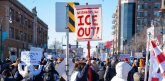 Crowd of protesters holding signs at a rally against ICE