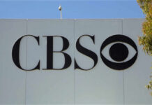 CBS logo displayed on a white wall with a blue sky background
