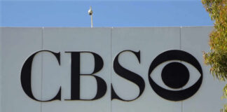 CBS logo displayed on a white wall with a blue sky background