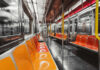 Interior of an empty subway train with orange seats and metallic surfaces
