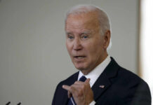 A man in a suit gesturing while speaking during a public address