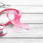 Cancer Misdiagnosis: Dull Pain’s Deadly Secret A pink ribbon next to a stethoscope on a wooden surface