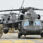 Military personnel preparing helicopters on an airbase