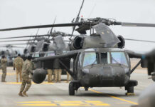 Military personnel preparing helicopters on an airbase