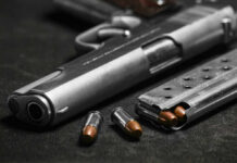Close-up of a handgun with bullets and a magazine on a dark surface