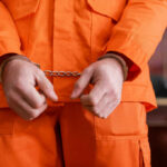 A person in an orange jumpsuit with handcuffs