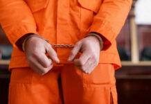 A person in an orange jumpsuit with handcuffs