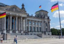 The Reichstag building in Berlin with German flags and visitors