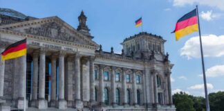 The Reichstag building in Berlin with German flags and visitors