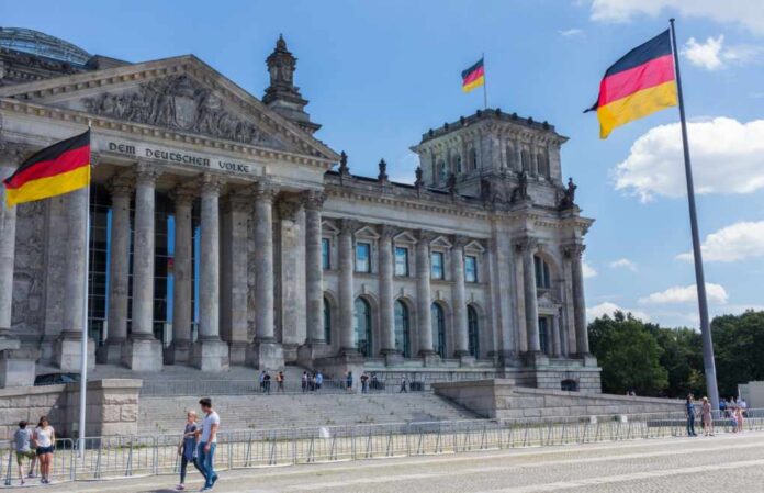 The Reichstag building in Berlin with German flags and visitors