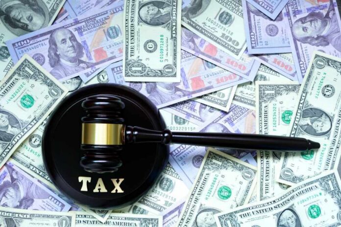 A gavel with the word 'TAX' on it placed on a background of US dollar bills