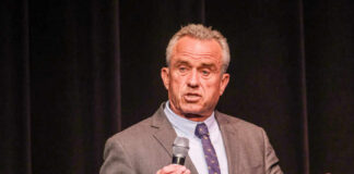 A man in a suit speaking into a microphone on stage