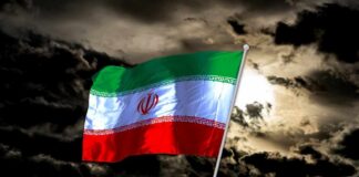 Iranian flag waving against a dark, cloudy sky