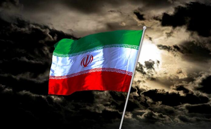 Iranian flag waving against a dark, cloudy sky
