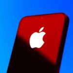 Close-up of a smartphone with the Apple logo against a red and blue background