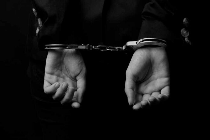 shutterstock_264530885.jpg Hands in handcuffs against a dark background
