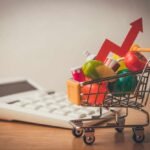Hunger Surge Shocks Wealthy UK A shopping cart filled with colorful grocery items next to a calculator and an upward trend arrow