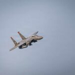 A military fighter jet flying against a clear sky