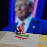 Map of Iran with push pins and a blurred figure in the background