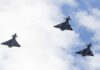 Three fighter jets flying in formation against a cloudy sky