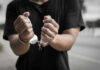 Close-up of hands in handcuffs against an outdoor background